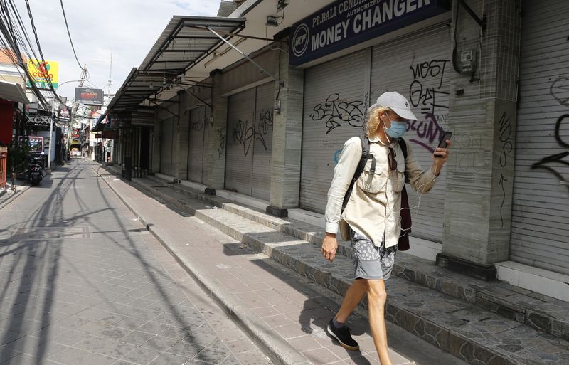 Turis berjalan di sepanjang toko yang tutup di Bali | Foto: AP Photo/Firdia Lisnawati