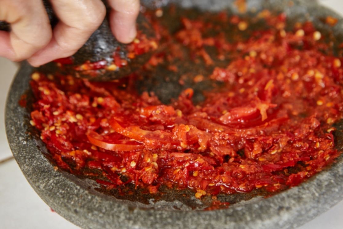 Proses pembuatan sambal dengan menggunakan cobek batu. © Bukalapak.com