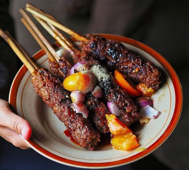 Sate Buntel khas Solo atau Surakarta, olahan sate daging kambing cincang yang dibuntel disajikan dengan pelengkap irisan bawang, tomat, kol, kecap, dan merica