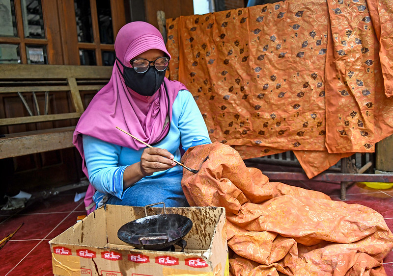 Seorang pengrajin batik sedang mewarnai dengan pewarna berbahan kayu alami@CIFOR/Flickr