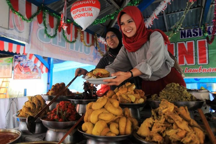 Penjual nasi kapau berada di atas sedang mengambilkan pesanan dengan sanduak