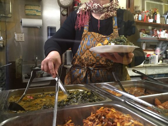 Bu Ena sedang menyajikan masakannya (philadelphianeighborhoods.com)